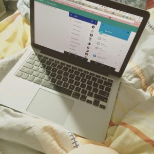 A laptop showing a social media interface on a bed, top view, showcasing technology use in a cozy setting.